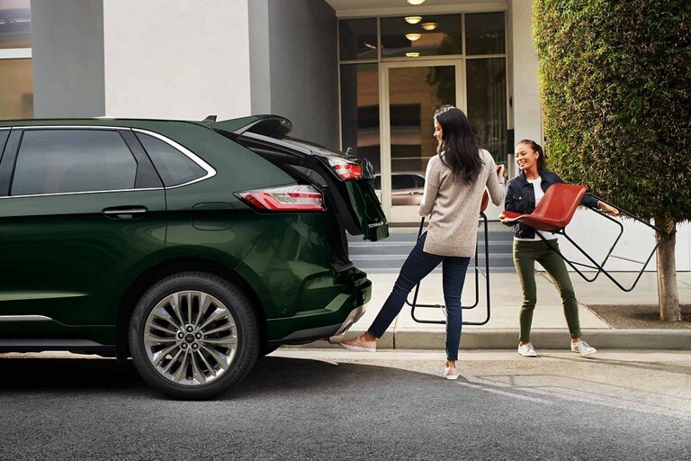 A woman holding a piece of furniture activating the hands-free foot-activated liftgate with her foot