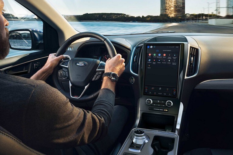 Primer plano de un hombre conduciendo una Ford Edge® 2024 con las manos en el volante térmico