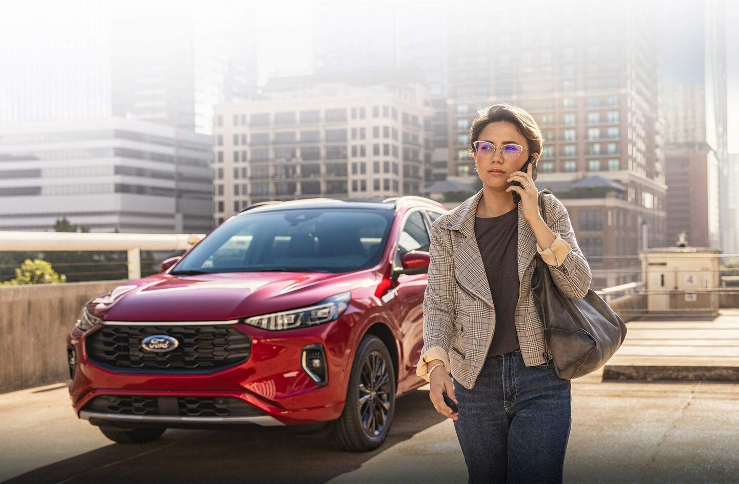 Una Ford Escape® 2023 estacionada y una mujer que camina hablando con un teléfono celular