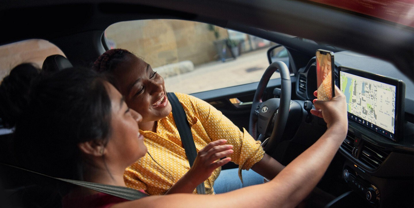 Primer plano del interior de una Ford Escape® 2023 con personas mirando sus smartphones
