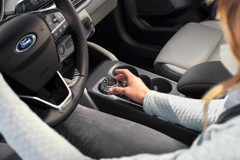 Interior of driver using the rotary gear shift dial in a 2023 Ford Escape®