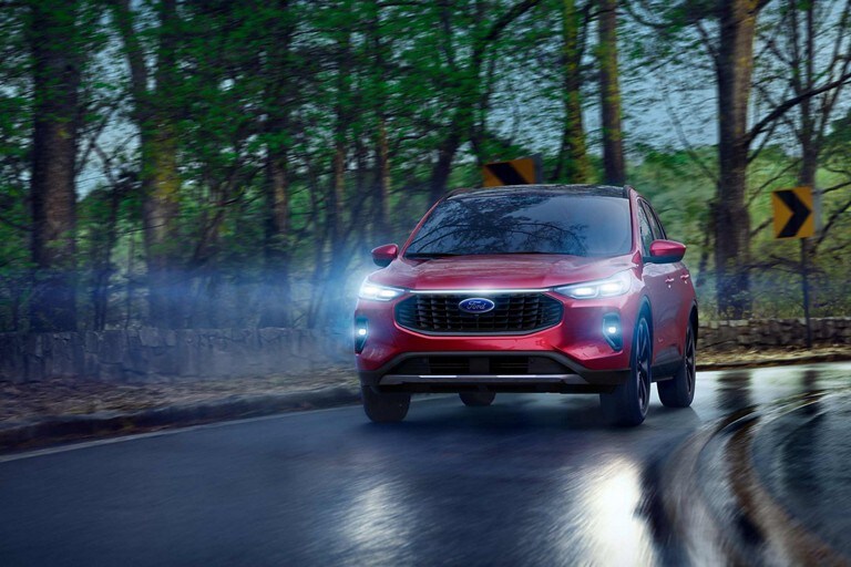 Una Ford Escape® 2023 en Rapid Red Metallic Tinted Clearcoat por una carretera sinuosa mojada