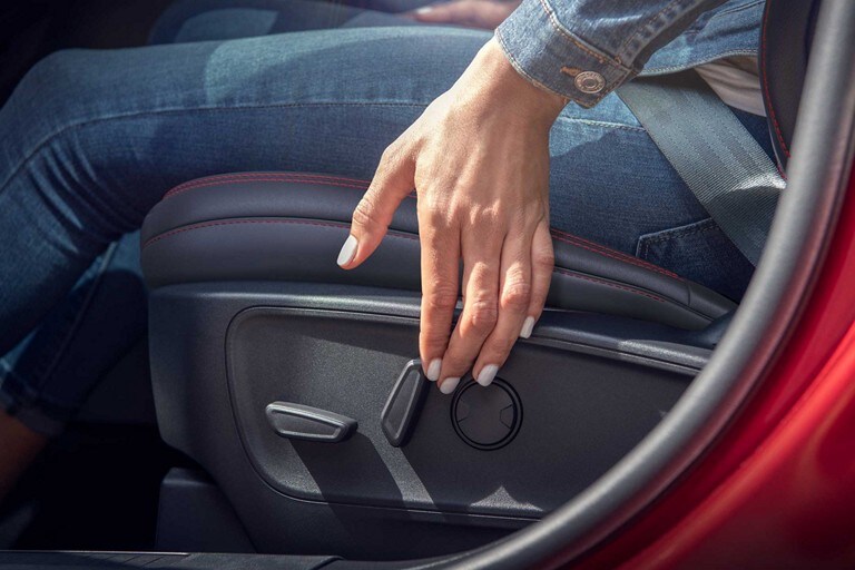 Primer plano de la mano de una mujer usando los controles del asiento del conductor