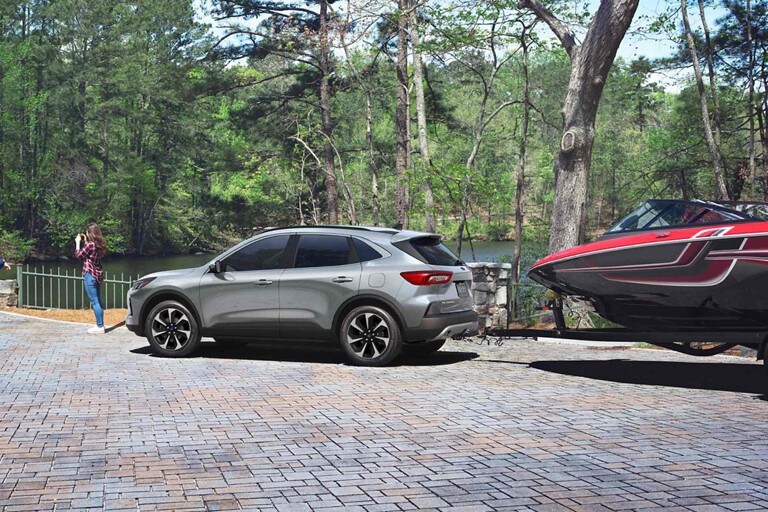 Profile view of an iconic 2024 Ford Escape The bow of a boat hitched to the Escape is visible