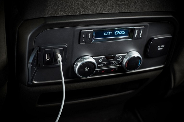 Primer plano del interior de una Ford Expedition 2023 que muestra un tomacorriente de CA de 110 V/150 W y Puertos Inteligentes USB