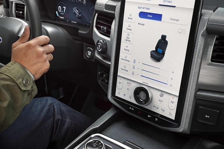 Close-up of a hand on a steering wheel to adjust the Multicontour Seats with Active Motion® massage on a 2023 Ford Expedition