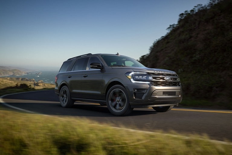 A 2024 Ford Expedition on a curving road with the ocean behind it