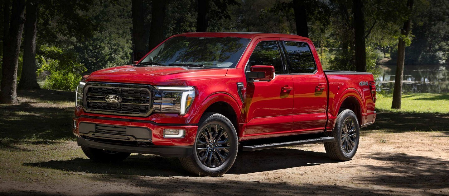 2024 Ford F-150® LARIAT® pickup in Rapid Red with the Black Appearance Package parked in a rustic setting