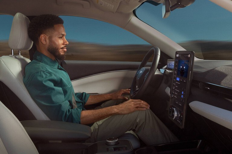 Hombre en una Ford Mustang Mach-E® 2023 con las manos sobre las rodillas mientras el vehículo es conducido por Ford BlueCruise