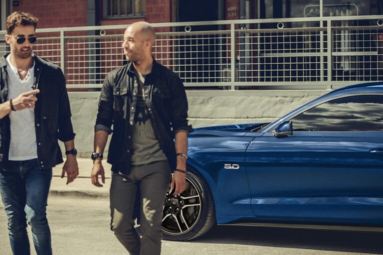 Two people walking away from a 2023 Ford Mustang® coupe