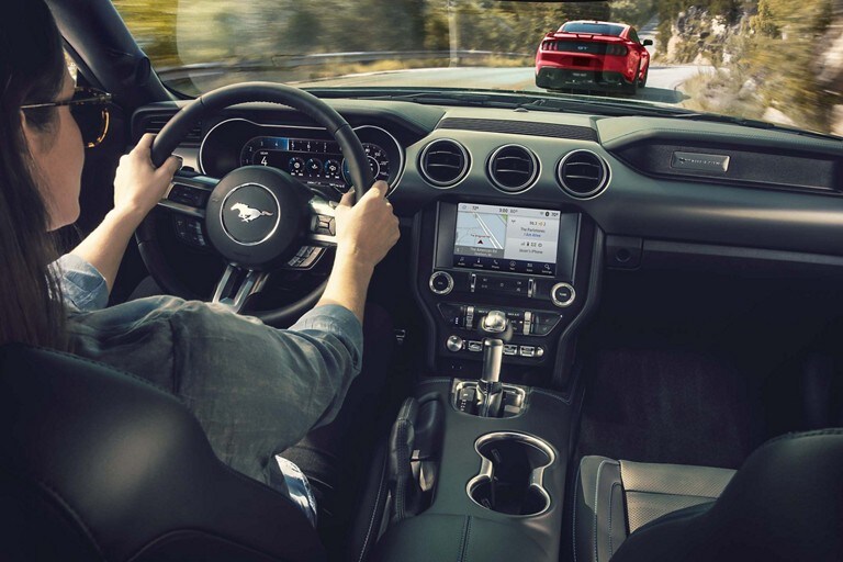 Una persona detrás del volante de una Ford Mustang® Coupe 2023 circulando por un camino de montaña
