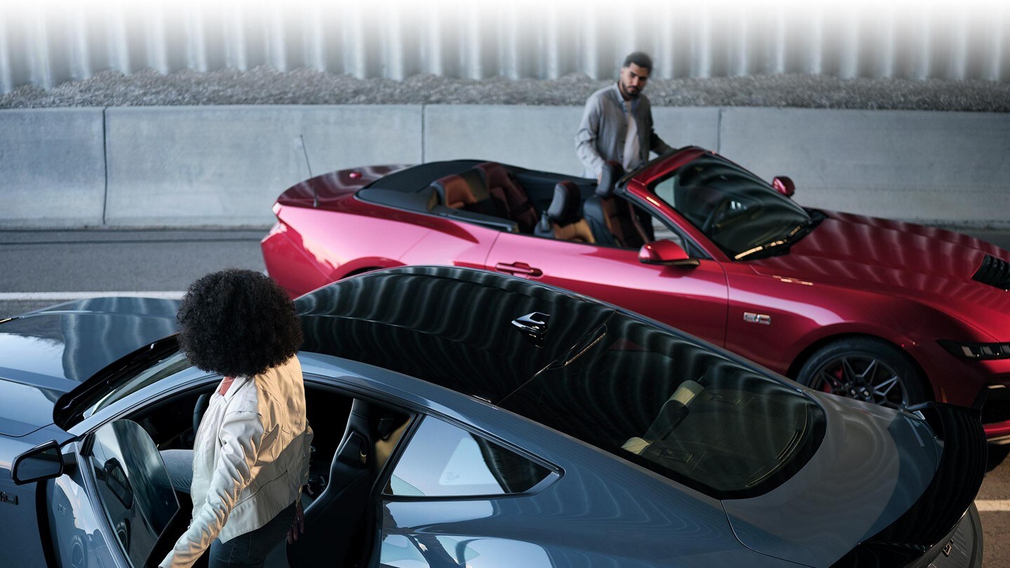Un Ford Mustang® 2024 cupé y convertible con dos conductores entrando a los vehículos