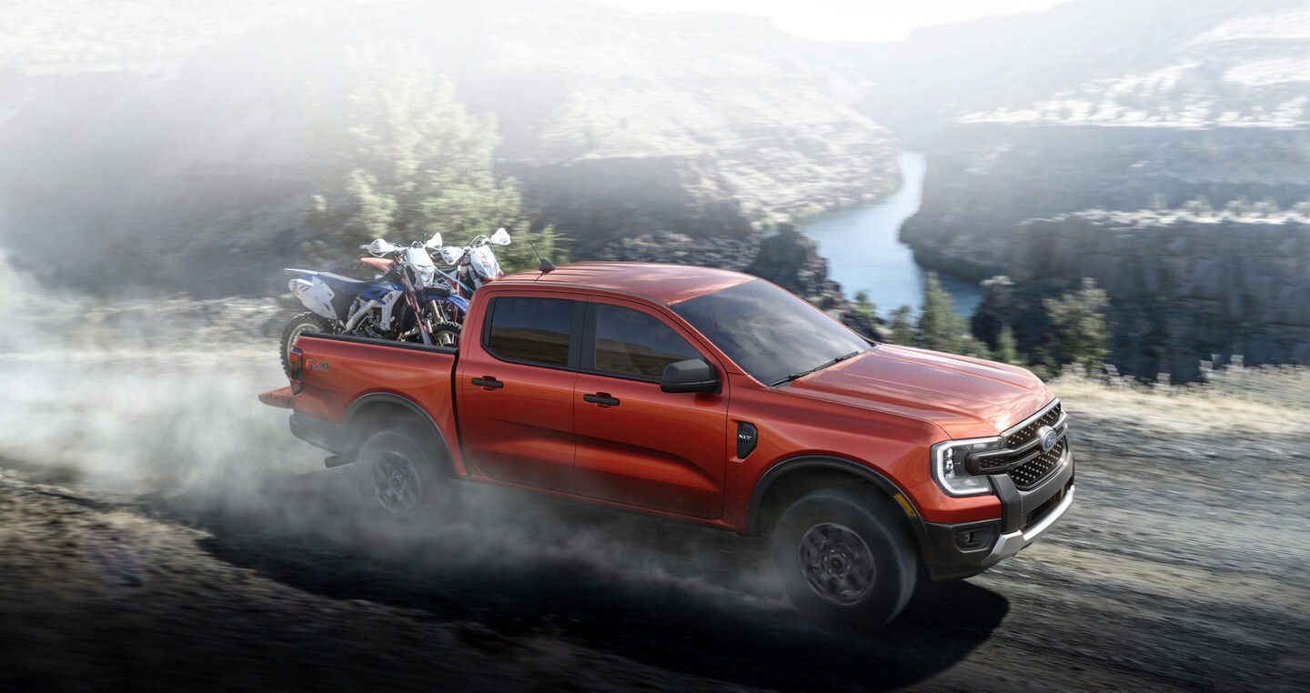 A 2024 Ford Ranger® in Hot Pepper Red with an extra cost option with dirt bikes being hauled and driven off-road