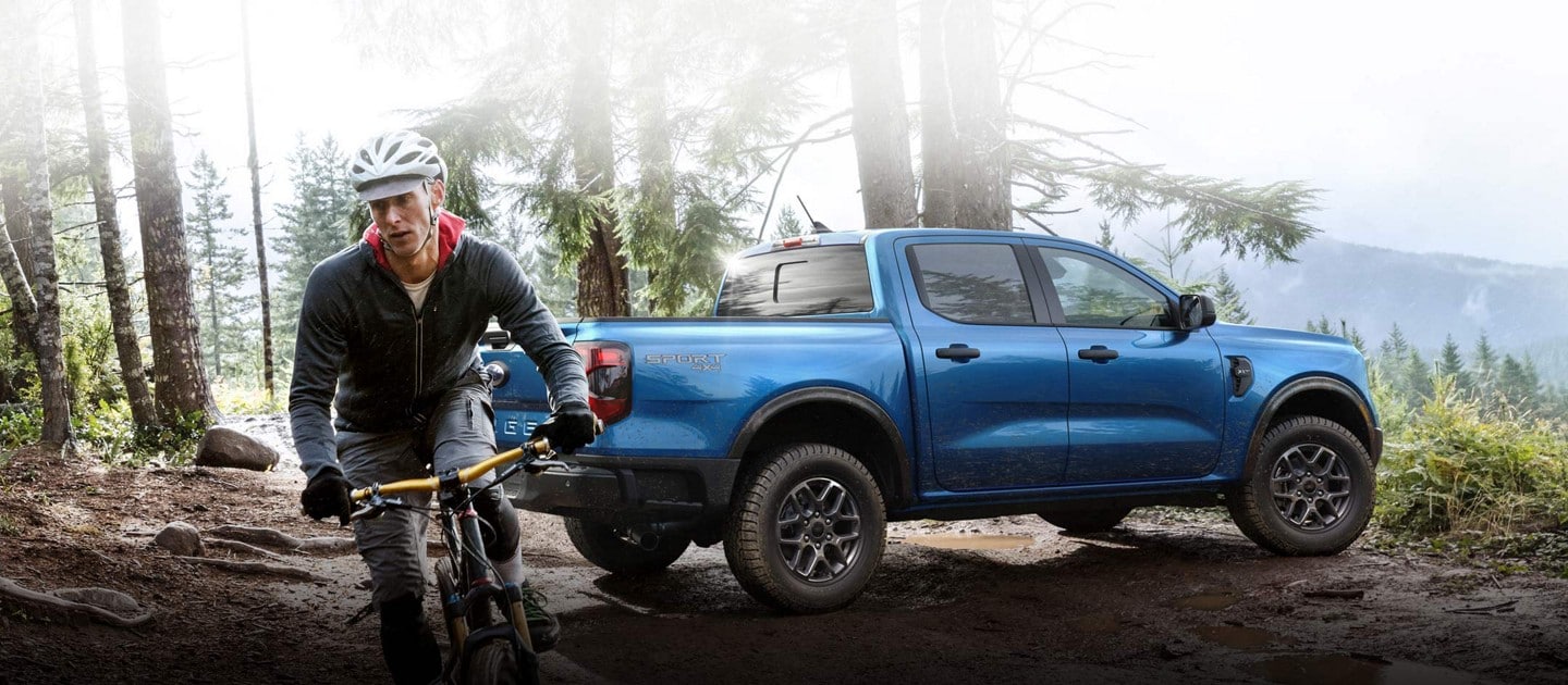 A 2024 Ford Ranger® XLT with Sport Appearance Package parked on a muddy hill near a person on a mountain bike
