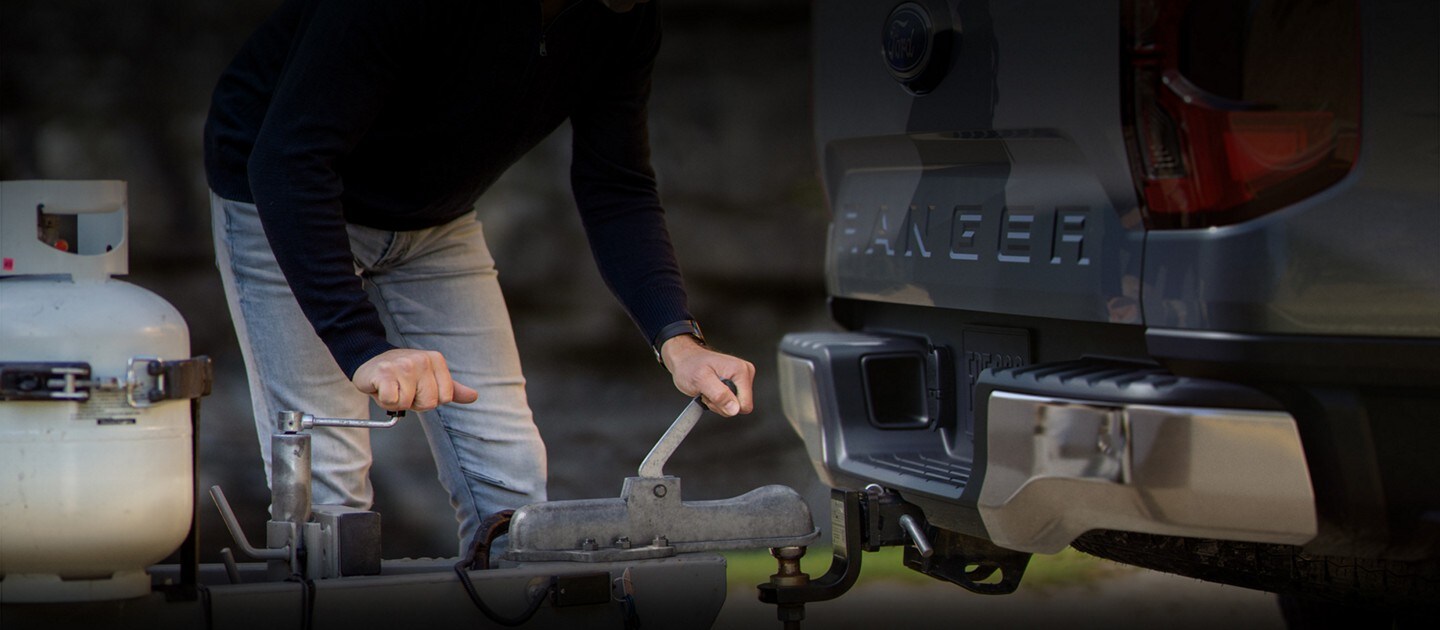 A person is hitching up their trailer to a 2024 Ford Ranger® model in a scenic location