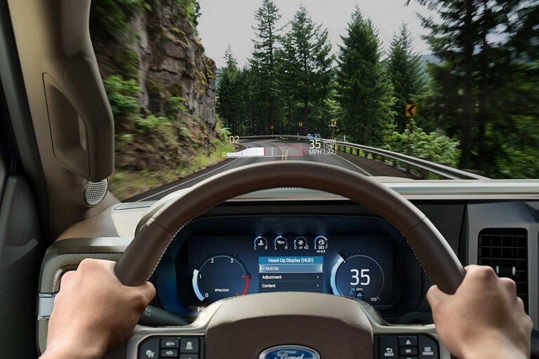 Close-up driver perspective of the digital instrument cluster and available Head-Up Display graphic on the windshield