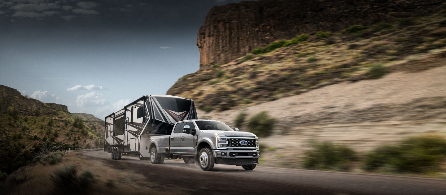 2024 Ford Super Duty® F-450® Limited DRW model pulling a camper trailer on a mountain road