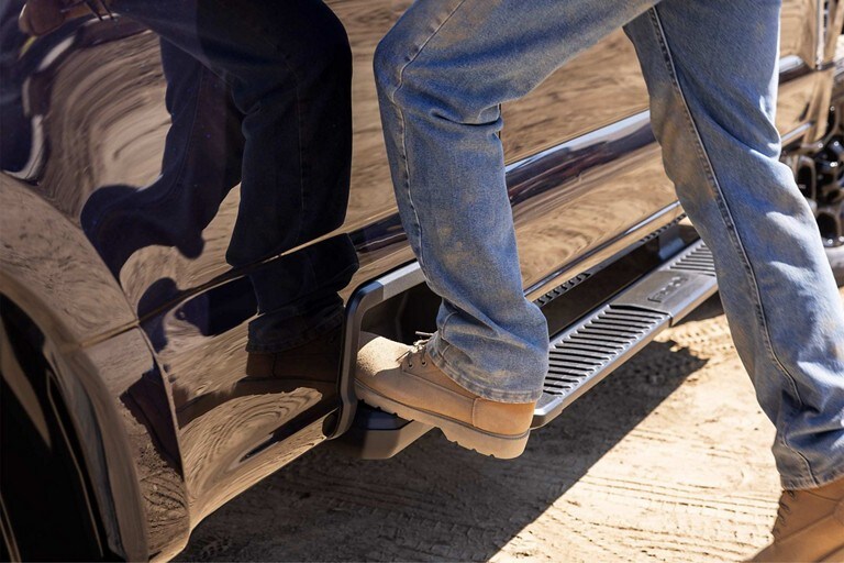Side by side close up of a person using the rear bumper step and integrated box side step