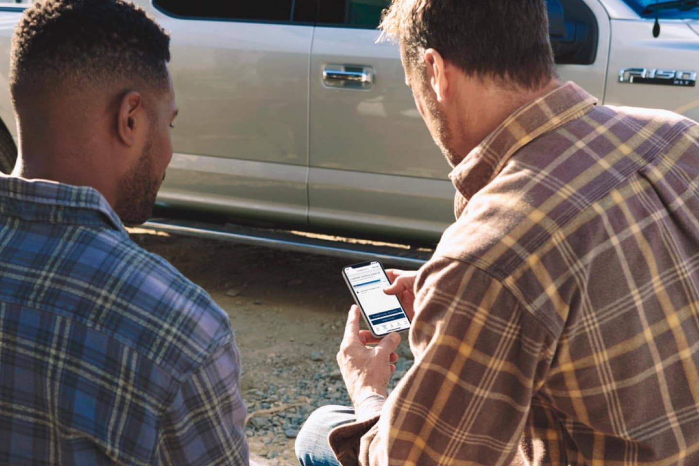 Dos hombres mirando la aplicación Ford Pro™ Telematics Drive en un smartphone
