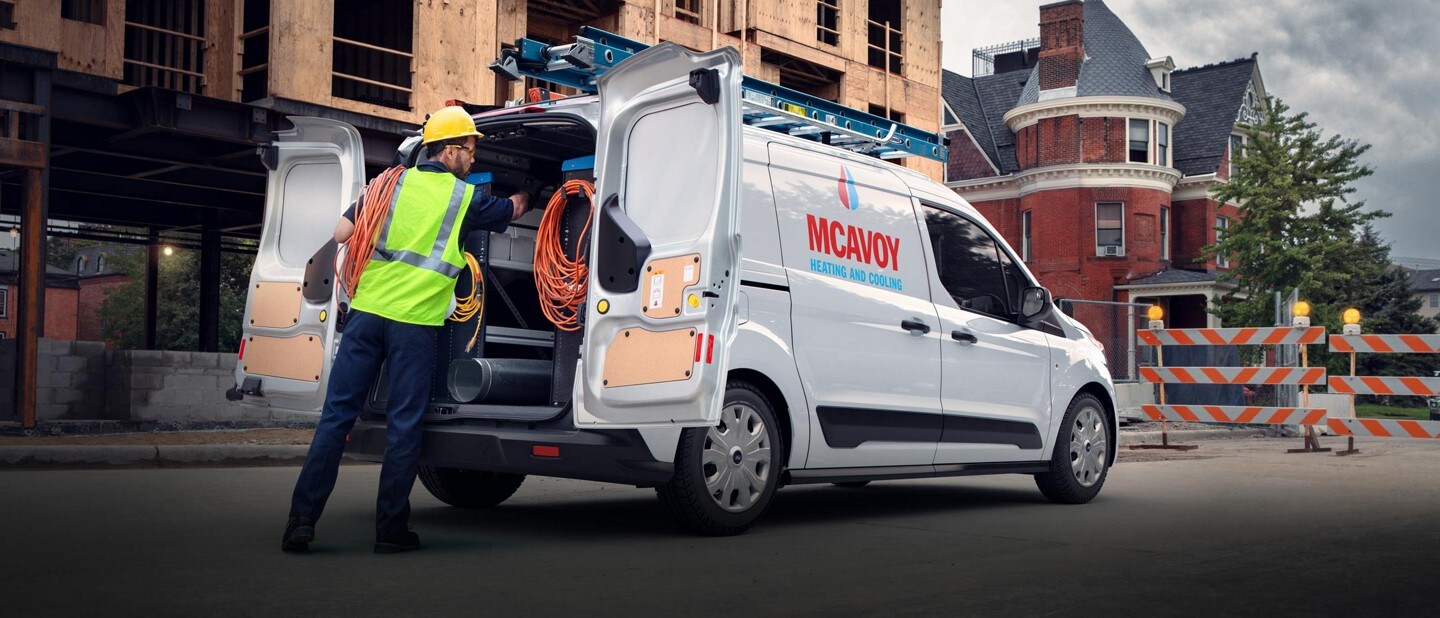 Man working on job site with a 2023 Ford Transit Connect Cargo Van shown with available aftermarket business graphics