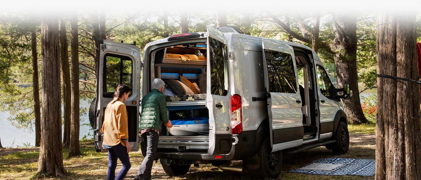 A couple unloading gear from the back of a 2023 Ford Transit Trail™ van