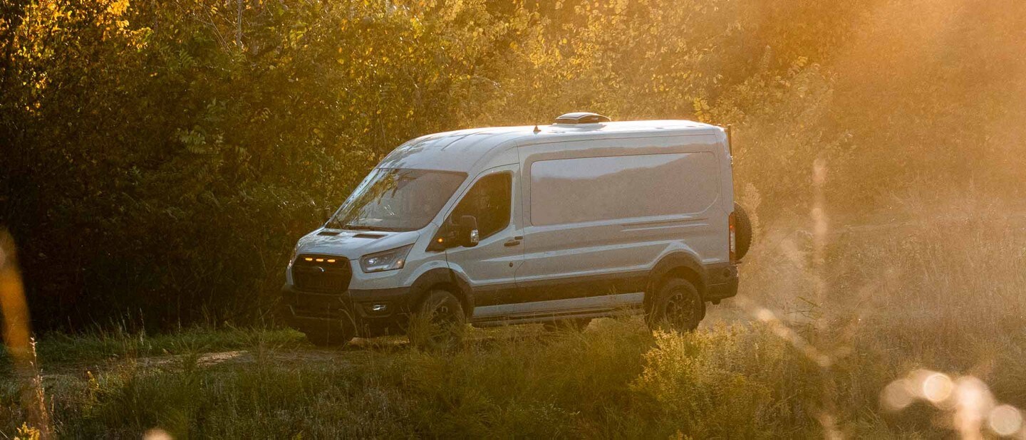 A 2023 Ford Transit Trail™ van being driven down a wooded road