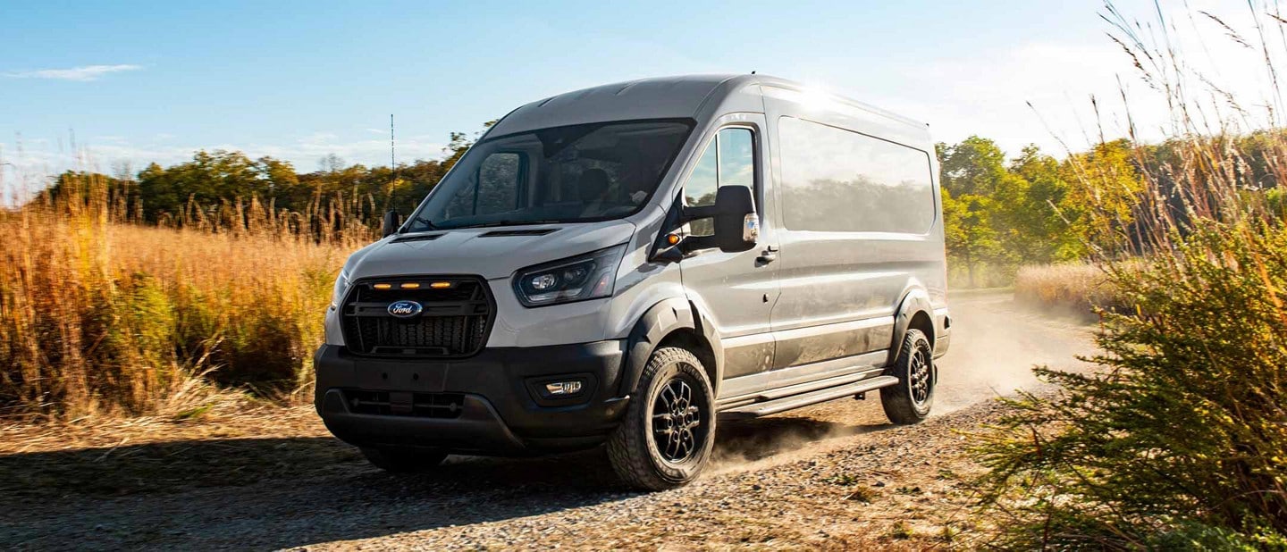 A 2023 Ford Transit Trail™ being driven down a dirt road