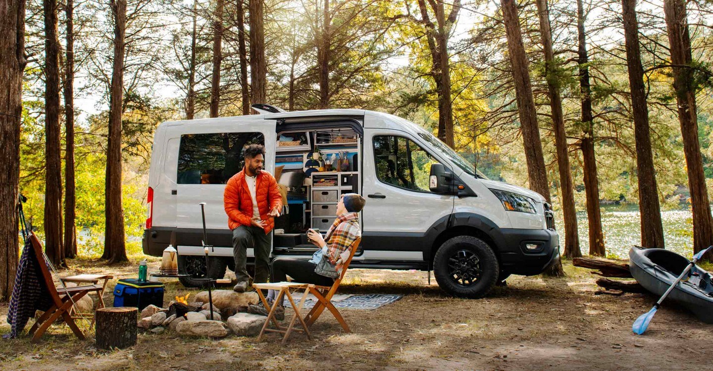 A man and woman sit outside a 2023 Ford Transit Trail™