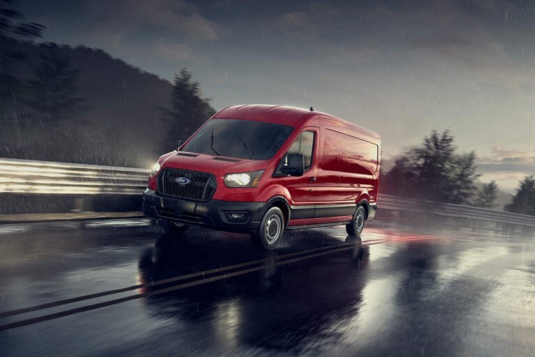 2023 Ford Transit® Van driving on wet pavement under a cloudy sky