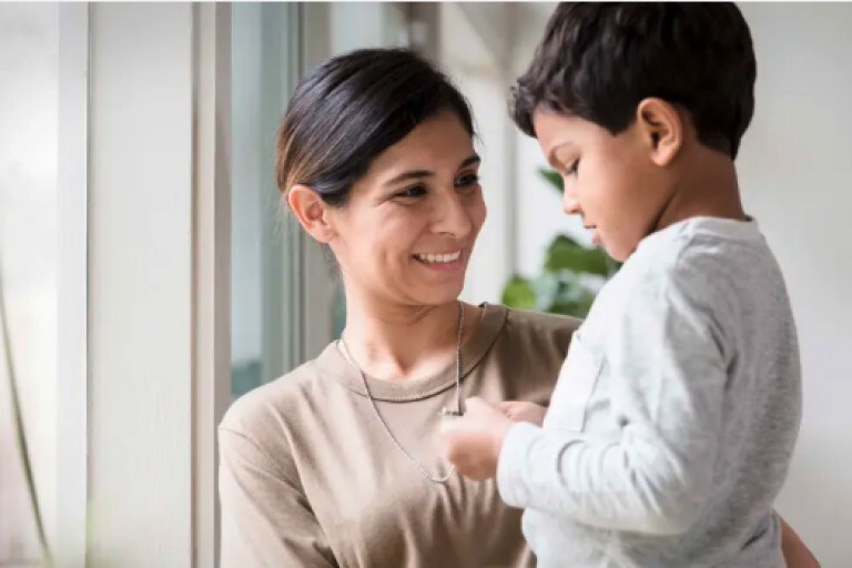 A veteran mother holding her child in front of a window.
