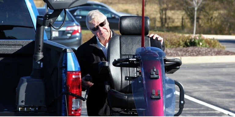 Man pulling a wheelchair from a pickup truck.