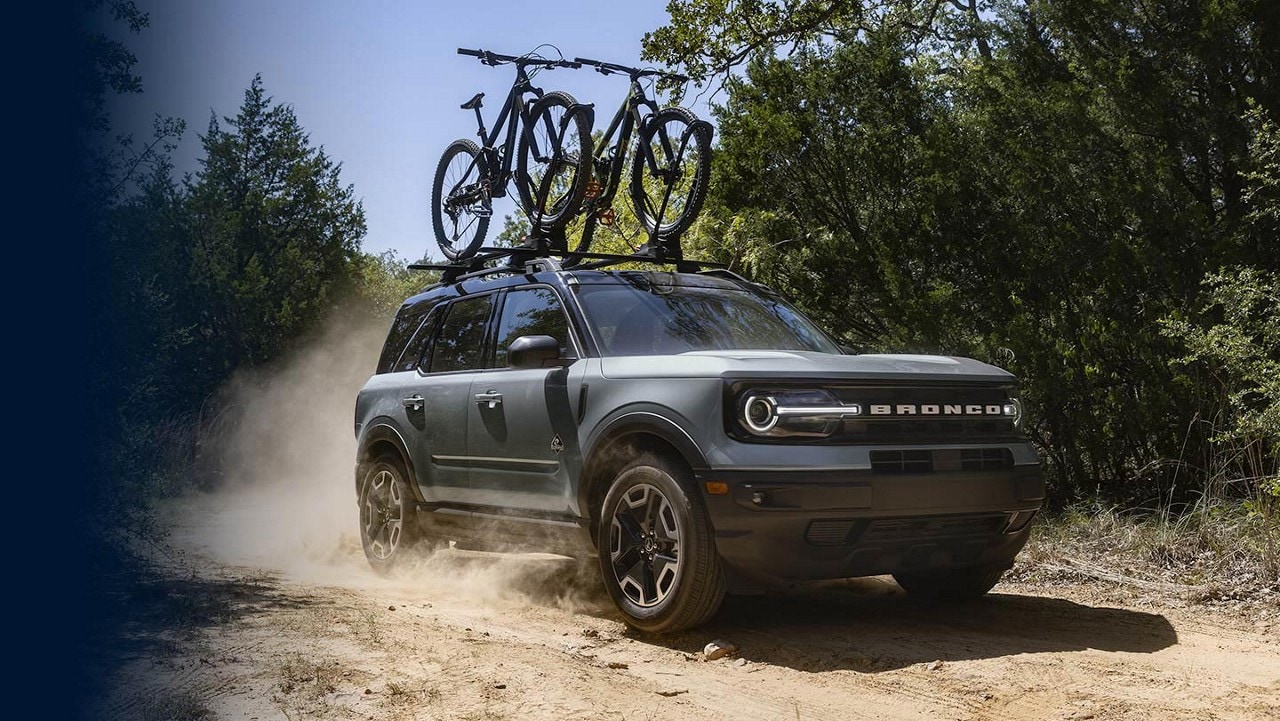 2024 Ford Bronco® Sport being driven on a dirt road with two bikes in the roof rack