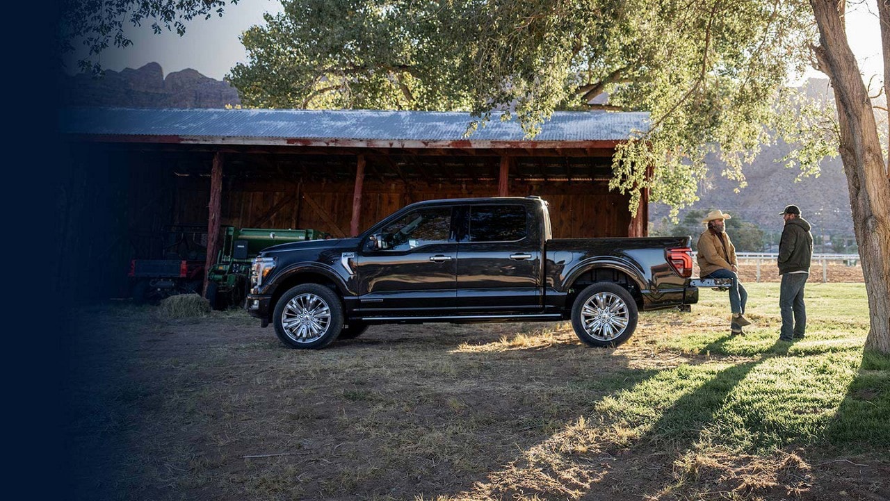 2024 Ford F-150® parked on a farm with a cowboy sitting on the tailgate talking to a man