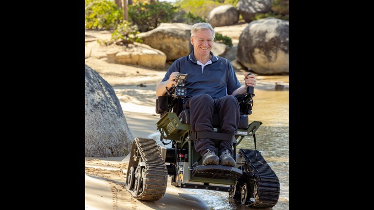  A man driving a trackchair on shoreline.