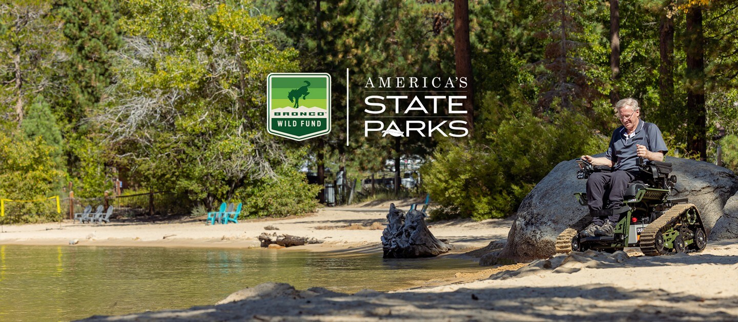A man in a trackchair on a beach.
