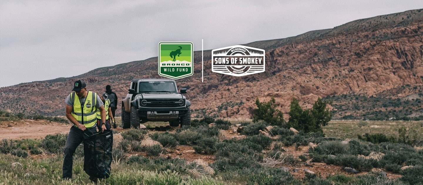 : Sons of Smokey volunteers picking up trash with a Ford Bronco® SUV and mountains in the background.