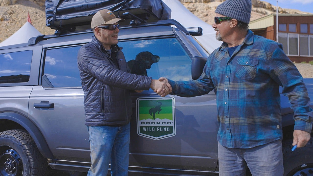 Bronco® SUV wrapped with the Bronco Wild Fund logo with two grant volunteers shaking hands