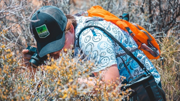 Front shot of a Bronco® SUV with a person flying a powered paraglider in the background