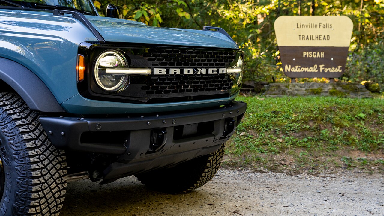 Bronco® SUV parked on a dirt road with a National Forest Trailhead sign in the background