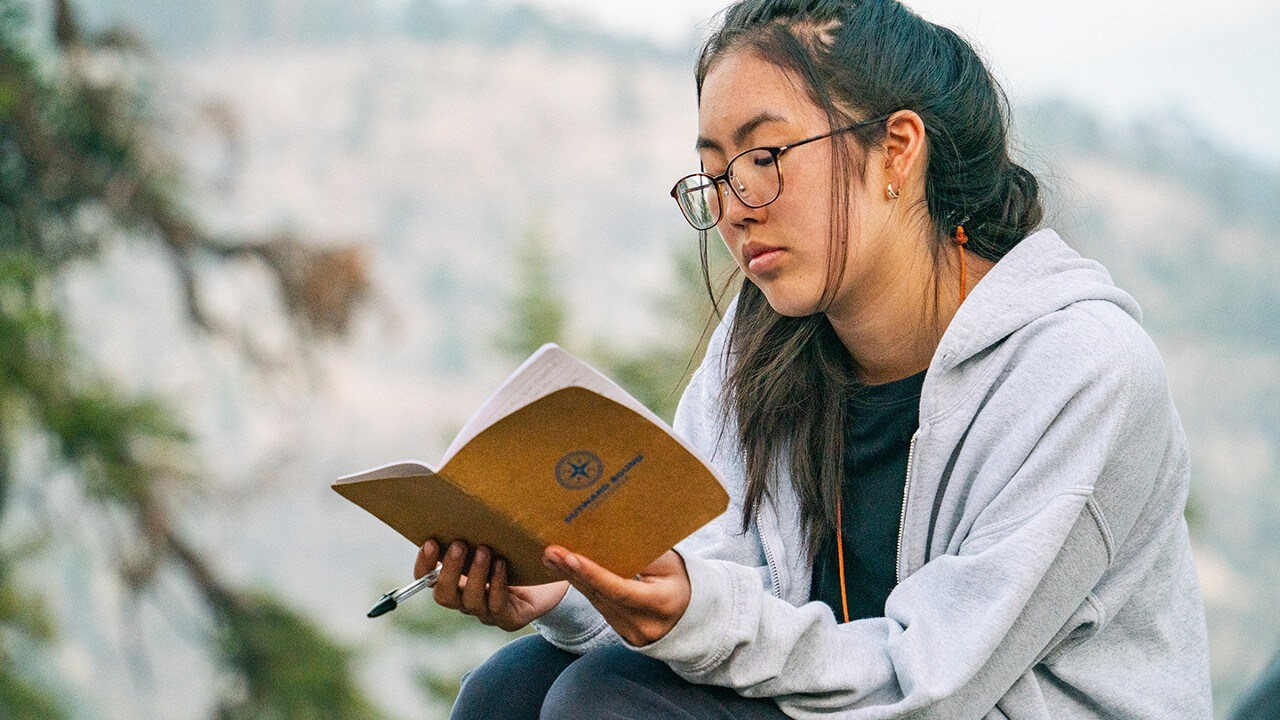 Outward Bound student reading from a notebook.