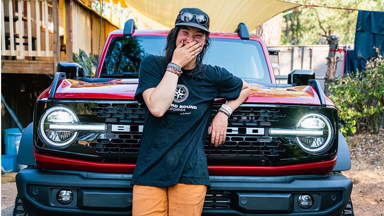 Smiling Outward Bound student standing in front of a Bronco® SUV.
