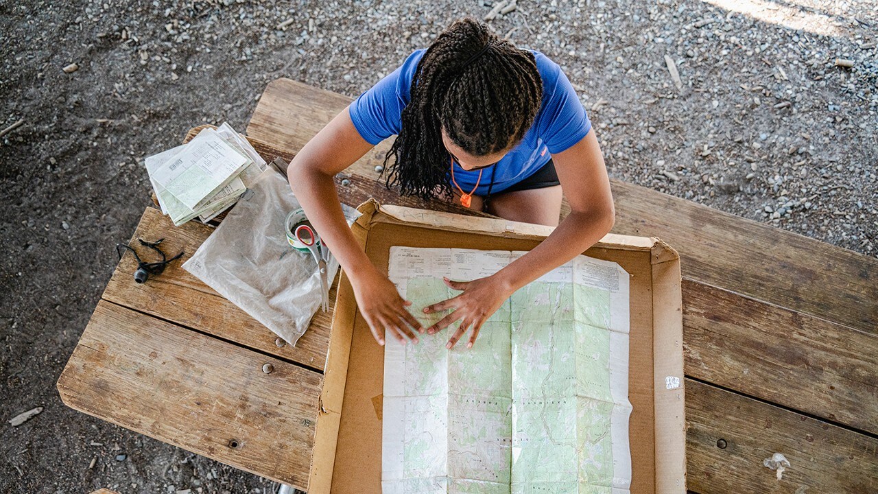 Outward Bound student sitting at a table looking at a map