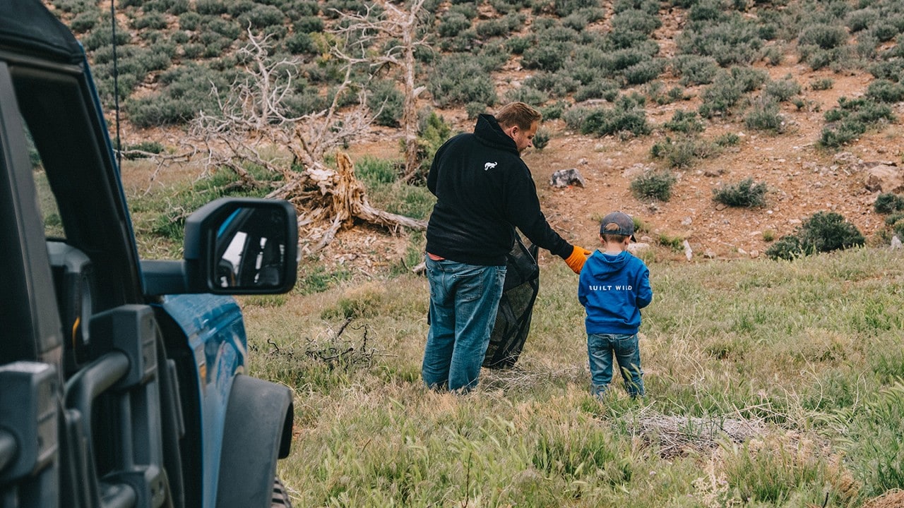 Man and child picking up trash in a field