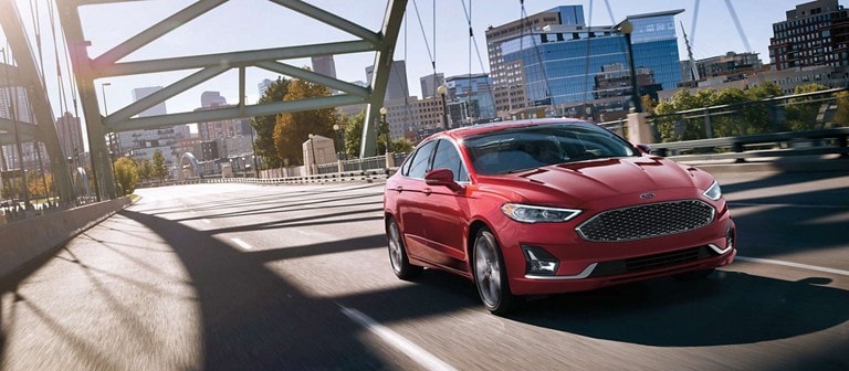 White 2020 Ford® Fusion shown parked in front of a brick building with patio lights strung up above it