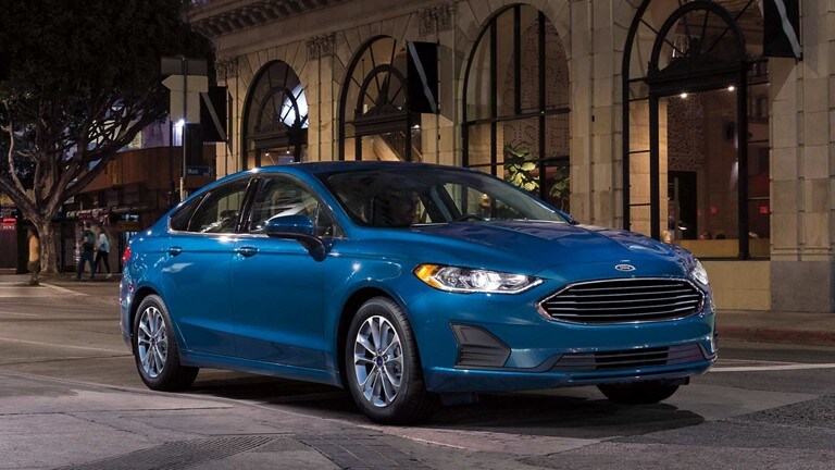Ford Fusion Hybrid SE in Victory Blue being driven in the city at night