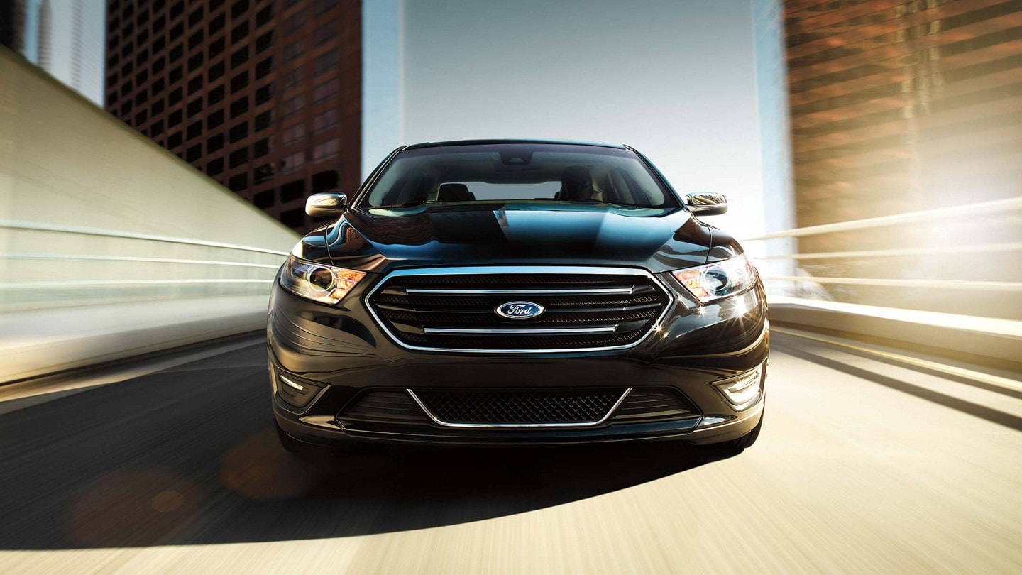 Front view of a Ford Taurus Limited in Absolute Black descending a ramp