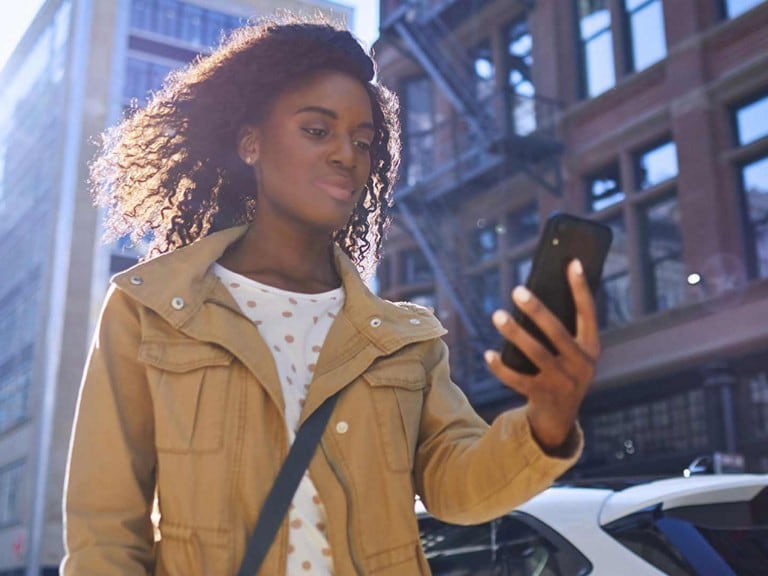 A woman checks the FordPass® App on her smartphone