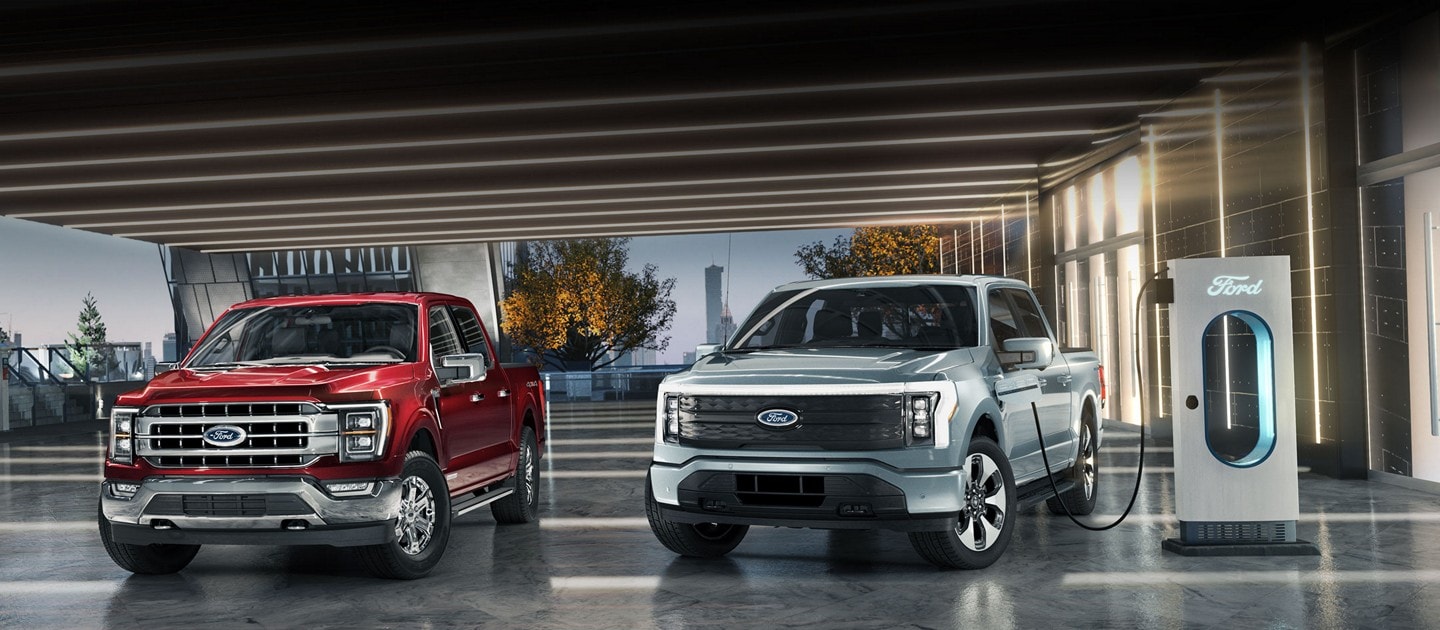A ford super duty pickup next to a ford f 150 lightning that is charging