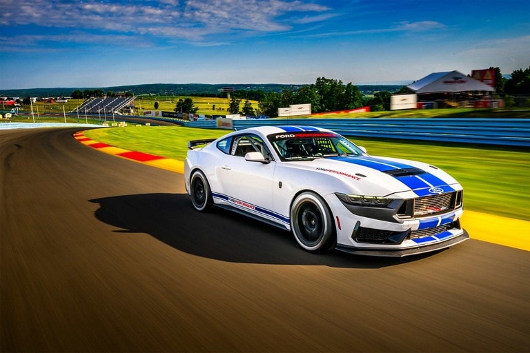 Ford Mustang® Dark Horse™ R race car being driven around a curve on a closed course