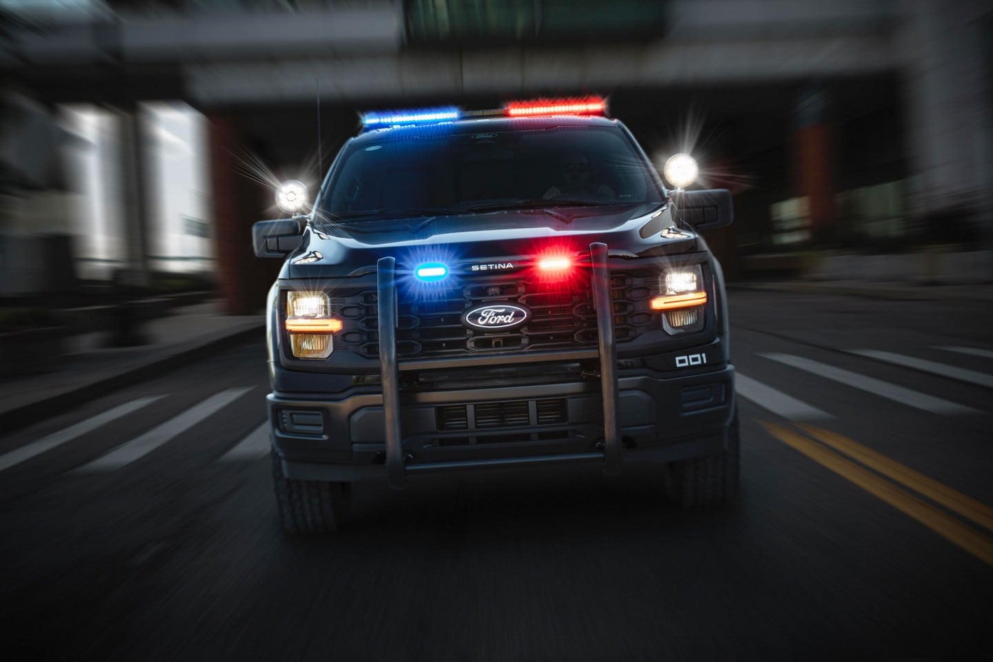 Front view of a 2024 Ford F-150® Police Responder with lights flashing being driven on a street